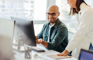 Software engineers using a computer and having a discussion in an office. Two creative business people working on a new coding project together.