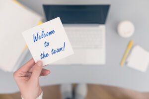 Woman clerk sitting holding note paper sticker with welcome to the team phrase. Business concept. Concept.