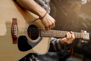 Young musician playing acoustic guitar close up