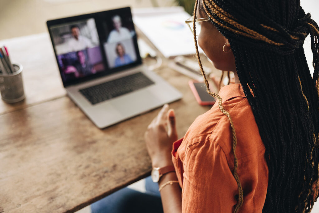 Graphic designer attending a virtual meeting with her clients. Creative female freelancer using a laptop for a video call. Young woman working on a new project in her home office.